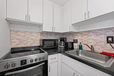 a kitchen with white cabinets and a stove and a sink at Sunny Miami Beach Retreat in Miami Beach