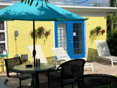a table with an umbrella in front of a house at Calypso Inn Wilton Gay Male Resort in Fort Lauderdale