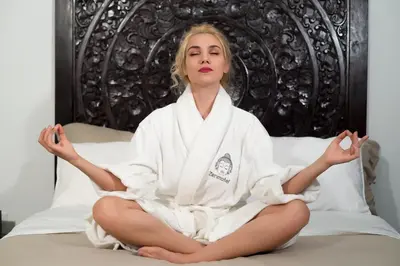 a woman sitting on a bed in a robe at Vive Zen Queen Room in Miami