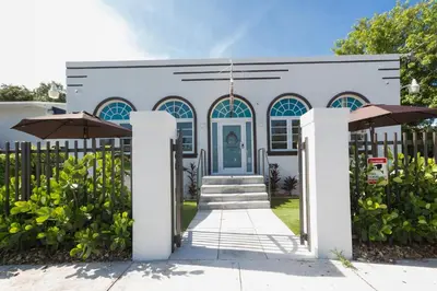 a white house with a blue door and a fence at Vive Zen Queen Room in Miami
