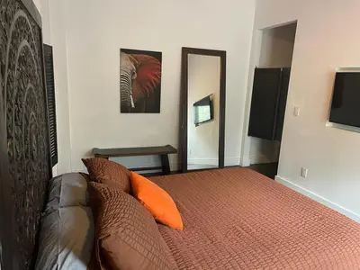 a bedroom with a bed with orange pillows and a mirror at Vive Zen Queen Room in Miami
