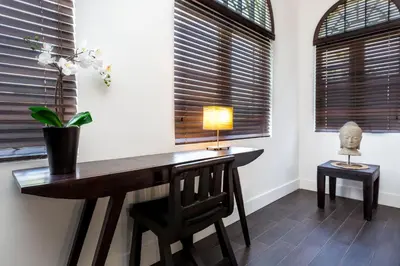 a desk with a lamp and a chair in a room with windows at Vive Zen Queen Room in Miami