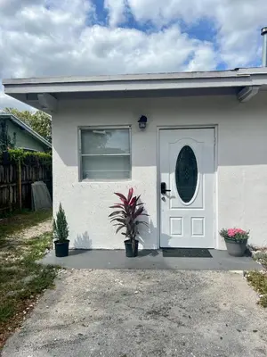 a white house with a door and two potted plants at Miami Gardens Comfort Suite by Hard Rock Stadium in Miami Gardens