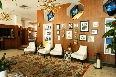 a waiting room with white chairs and pictures on the wall at Hotel Croydon in Miami Beach