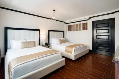 a bedroom with two beds and a door at Hotel Croydon in Miami Beach