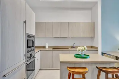 a kitchen with white cabinets and a table with two chairs at Oceanfront Condo Direct Ocean & Beach Club Access in Hollywood