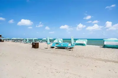 a group of chairs and umbrellas on a beach at Ocean View Luxury Carillon Condo at Beach Access C616 in Miami Beach