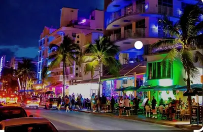 a group of people walking down a city street at night at Home Sweet Home in Miami