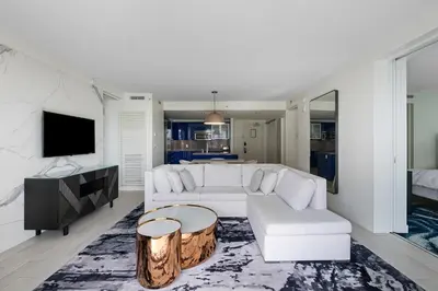 a living room with a white couch and a tv at Resort-Style Residence Beachfront Condo Oasis in Fort Lauderdale