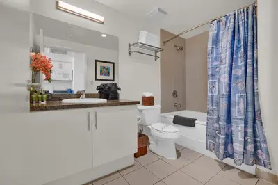 a bathroom with a toilet and a shower curtain at Beautiful Blue & Gold Studio With Ocean View in Miami