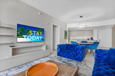 a living room with blue chairs and a flat screen tv at Heaven Resort - 2BDR BEACH HOME WITH OCEAN VIEW HOLLYWOOD! in Hollywood