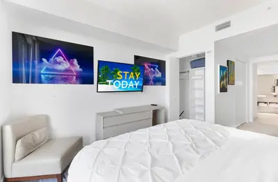 a white bedroom with a bed and a tv on the wall at Heaven Resort - 2BDR BEACH HOME WITH OCEAN VIEW HOLLYWOOD! in Hollywood