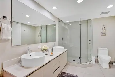 a bathroom with two sinks and a shower and a toilet at Sky-High Spacious Ocean View Condo 4 BDRS 3 BATH in Hallandale Beach