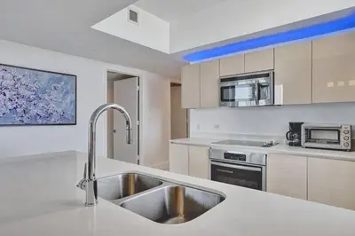 a kitchen with a sink and a microwave at Sky-High Spacious Ocean View Condo 4 BDRS 3 BATH in Hallandale Beach