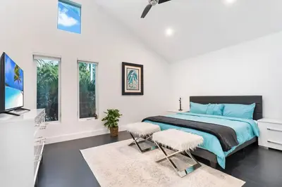 a bedroom with a bed with two chairs and a tv at Best Sunset View on the Bay with Pool in Miami Beach