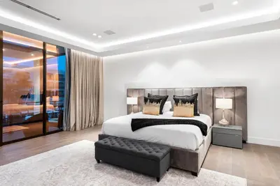 a bedroom with a king sized bed and a black ottoman at Boardwalk Mansion in Fort Lauderdale