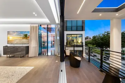 a living room with a tv and a balcony at Boardwalk Mansion in Fort Lauderdale