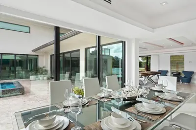 a dining room with a glass table and chairs at Villa Paraiso in Hollywood
