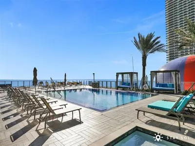 a swimming pool with lounge chairs and the ocean at Upper Level Penthouse - Amazing Views Beach & Intracoastal in Hollywood