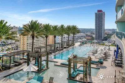 a pool with chairs and palm trees on a building at Upper Level Penthouse - Amazing Views Beach & Intracoastal in Hollywood
