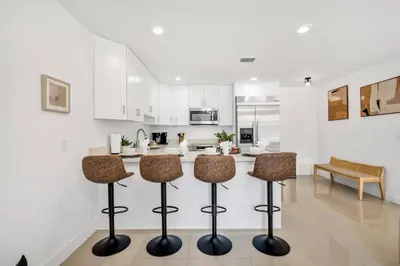 a kitchen with white cabinets and a counter with stools at Urban Seaside in Dania Beach