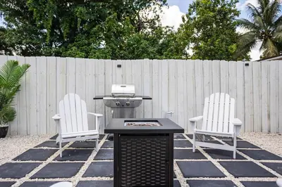 two chairs and a grill in a backyard with a fence at Coco Loco - Little Havana in Miami
