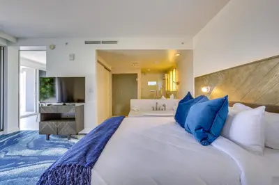 a bedroom with a large white bed with blue pillows at Fort Lauderdale Condo with Veranda and Ocean View! in Fort Lauderdale