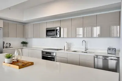 a kitchen with white cabinets and stainless steel appliances at Lower Penthouse 3BD 3BA - Beach Pool Gym in Hallandale Beach