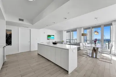 a white kitchen with a table and a dining room at Modern Ocean View 3 Bedroom Condo Resort Amenities in Hallandale Beach