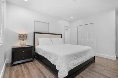 a white bedroom with a bed and a night stand at Villa Mia Cozy Home in the heart of Miami in Miami