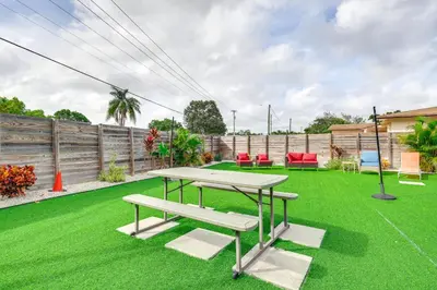 a patio with a table and a bench on the grass at Private Pool and Patio Fort Lauderdale Home! in Fort Lauderdale