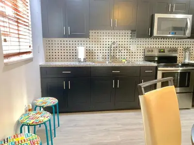 a kitchen with black cabinets and a sink and stools at Home Sweet Home Near Malls and Airport and Hwy in South Miami