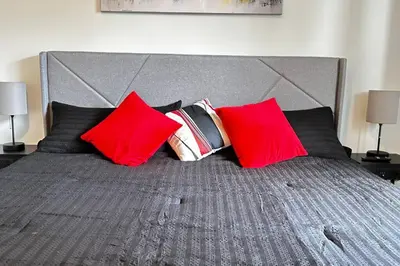 a bed with red and black pillows on it at Sunny Delight Home Near Airport in Hollywood