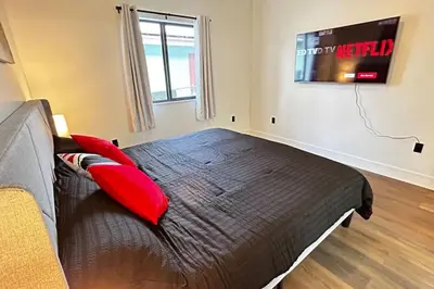 a bedroom with a bed with red pillows and a tv at Sunny Delight Home Near Airport in Hollywood