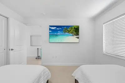 a bedroom with two beds and a picture of a beach at Villa Capri Cottage in the heart of Miami in Miami