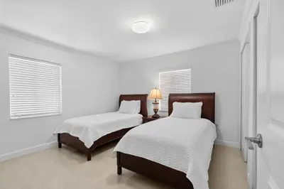 two beds in a room with white walls and windows at Villa Capri Cottage in the heart of Miami in Miami