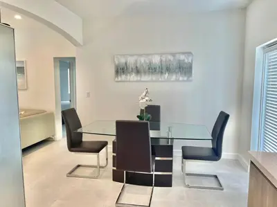 a dining room with a glass table and black chairs at Villa Gia Large Home Near Brickell Miami Beach in Miami