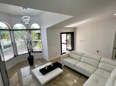 a living room with a white couch and some windows at Sunny Getaway: Relaxing Miami Home in Tamiami
