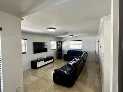 a living room with a black couch and a television at Sunny Getaway: Relaxing Miami Home in Tamiami