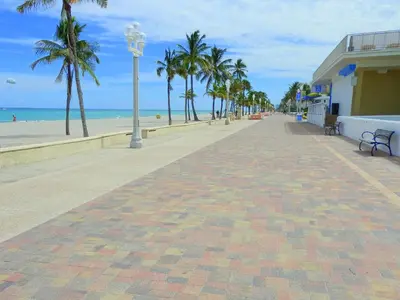 a brick sidewalk next to a beach with palm trees at 311-22 Beachside in Hollywood