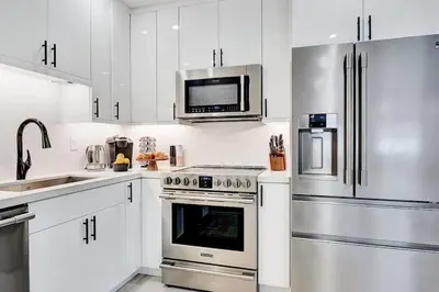 a kitchen with white cabinets and stainless steel appliances at Soleil @ Casa Del Sol in Fort Lauderdale
