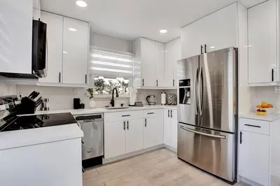 a kitchen with white cabinets and a stainless steel refrigerator at Oceana @ Casa Del Sol in Fort Lauderdale