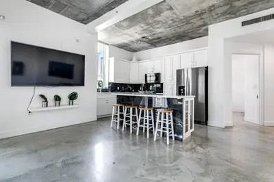 a white kitchen with bar stools and a tv on the wall at Spectacular 2-Br Apartment 4 people 1107 in Miami