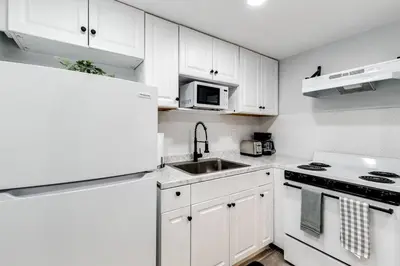 a white kitchen with white cabinets and a sink at Loft style 1b Apt , Fast Wi-Fi Virg14 in Miami
