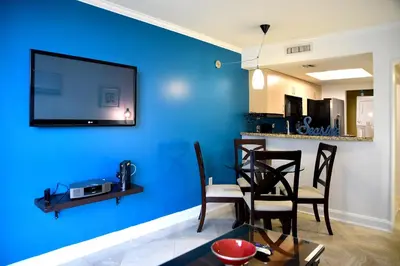 a living room with a blue wall with a tv at Relaxing Condo Hotel In The Grove, Free Parking in Miami