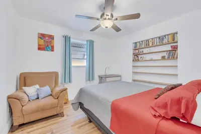 a bedroom with a bed and a chair and a ceiling fan at Tranquil Pool Home in Hollywood Close to Beach Airport in Hollywood