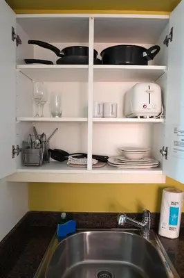 a kitchen counter with a sink and a shelf with dishes at Stunning 12th Floor Studio In The Heart Of Grove in Miami