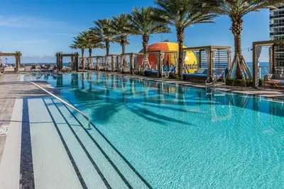 a large swimming pool with palm trees and a roller coaster at Splendid Resort - Oceanview 1BDR & 1BA Apt Right on the Beach, Heated pool, GYM in Hollywood