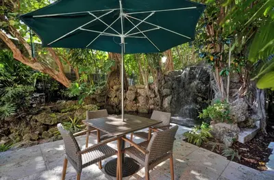 a table with a green umbrella and two chairs at Treetop Retreat! Cozy 2 Bedroom In Heart Of Grove in Miami