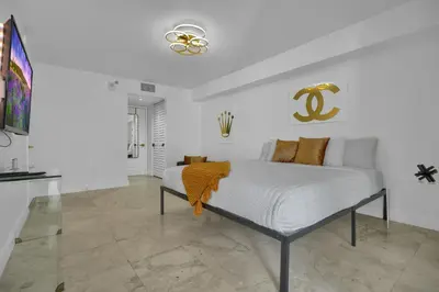 a white bedroom with a bed with a yellow blanket on it at Zeus' Sanctuary Ocean View In Brickell Miami in Miami